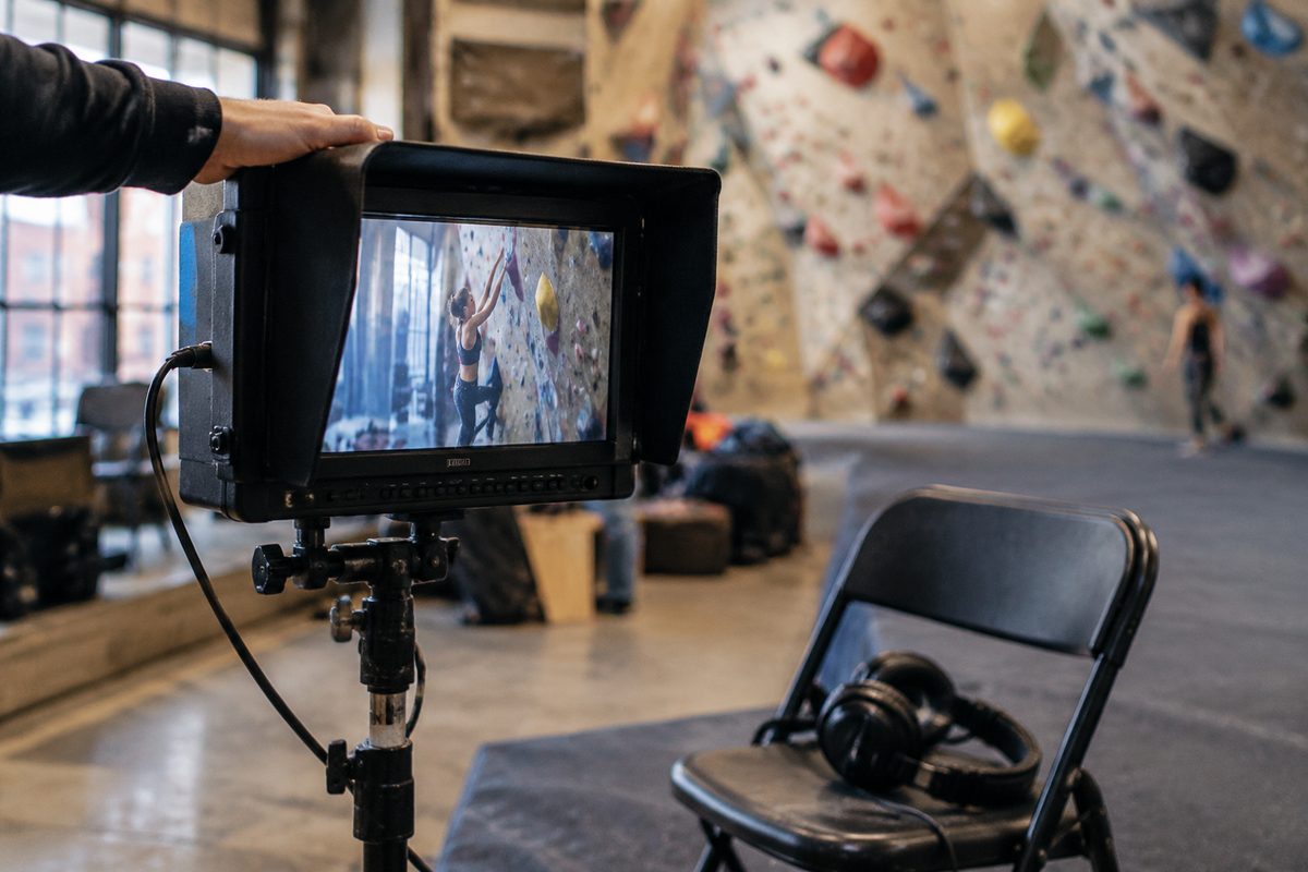 The director's monitor showing the climber on the wall, the real wall blurred behind